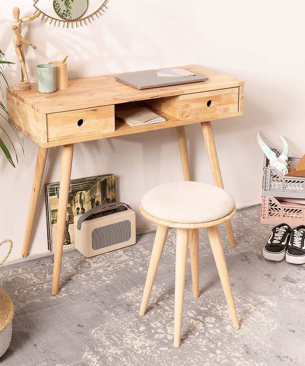 Un petit bureau en bois clair à tiroirs et un tabouret, faciles à caser