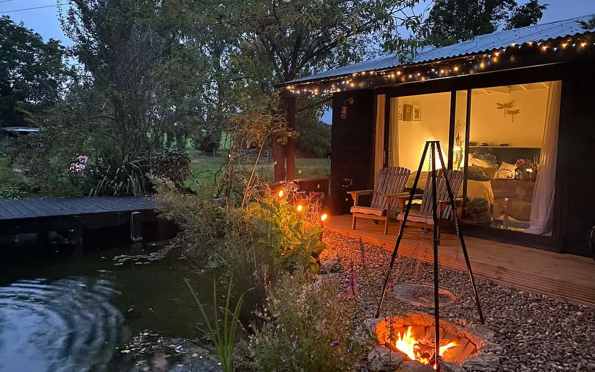 Vue extérieure de la mini maison avec sa terrasse en face de l'étang